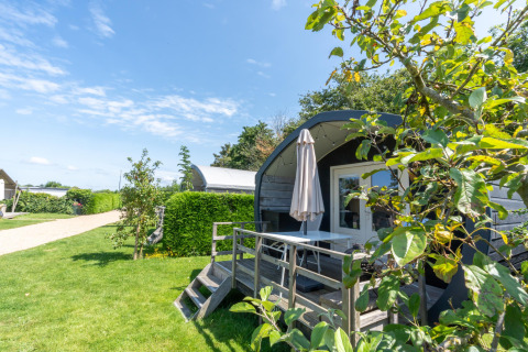 Vakantiehuisje met terras en parasol in 7Huizen aan Zee, omgeven door groen in Zeeland, Nederland.