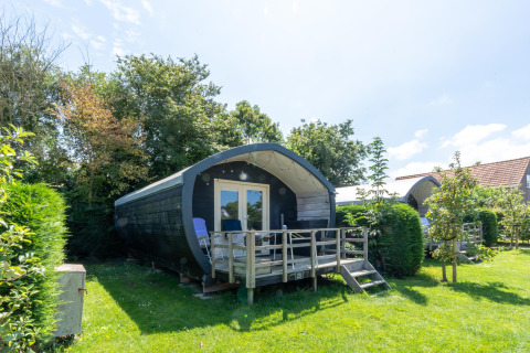 Holiday cabin with terrace and chairs surrounded by greenery at 7Huizen aan Zee holiday park in Zeeland, Netherlands.