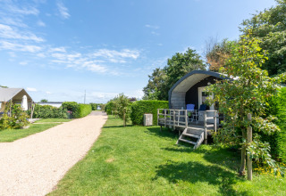 Sunny holiday park at 7Huizen aan Zee in Zeeland, Netherlands, with green lawns, cabins, and a gravel path.