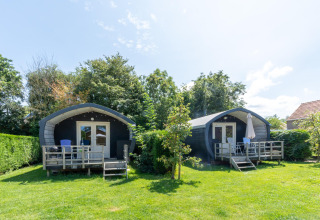 To hyggelige feriehytter med terrasser og havemøbler i grønne omgivelser i 7Huizen aan Zee, Zeeland.