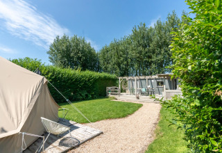 Sonniger Campingplatz bei 7Huizen aan Zee, Zeeland, mit Zelt, Rasenfläche und Holzterrasse im Grünen.