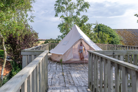 Person verlässt ein Zelt auf einer Holzterrasse bei 7Huizen aan Zee, einem Ferienpark in Zeeland, Niederlande.