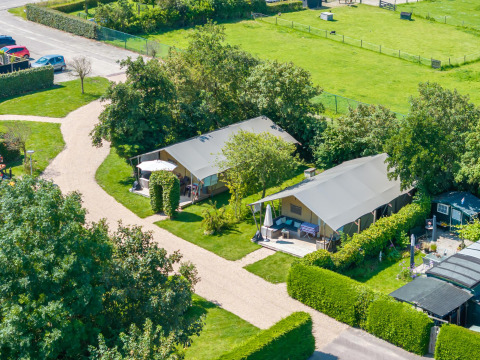 Vista aérea de dos cabañas rodeadas de vegetación en 7Huizen aan Zee, un parque vacacional en Zelanda, Países Bajos.