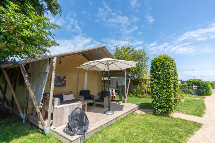 Cozy holiday cabin with a shaded terrace and umbrella at 7Huizen aan Zee holiday park in Zeeland, Netherlands.