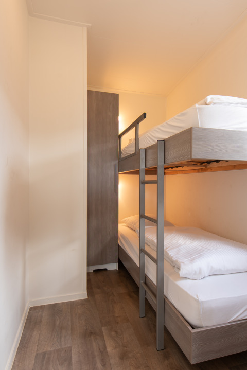Moderne stapelbed en kleerkast in een knusse kamer van Comfort Lodge te Kompas Camping Nieuwpoort, België.