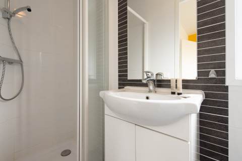 Baño moderno en una tiny house Comfort Lodge en Kompas Camping Nieuwpoort, Bélgica, con ducha y lavabo.