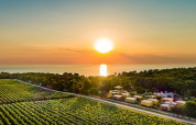 Tramonto al Camping Aminess Maravea in Istria, Croazia, con campi verdi, bungalow e il mare sullo sfondo.
