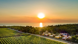 Zonsondergang bij Camping Aminess Maravea in Istrië, Kroatië, met groene velden, chalets en uitzicht op zee.