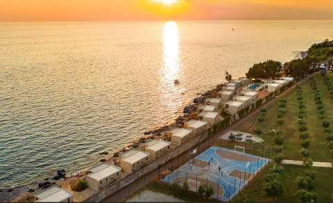 Coucher de soleil au Camping Aminess Maravea, Istrie, Croatie, avec cabanes et terrain de sport en bord de mer.