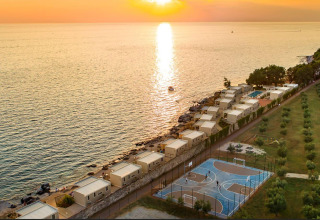 Solnedgang over Camping Aminess Maravea i Istrien, Kroatien, med moderne hytter og sportsplads ved kysten.