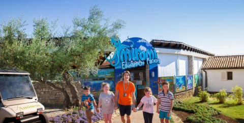 Children and an adult outside Mirami Edutainment Factory at Camping Aminess Maravea in Istria, Croatia, on a sunny day.