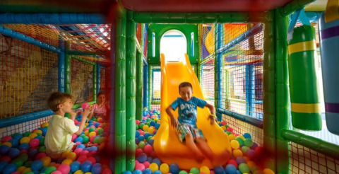Kinder spielen im bunten Bällebad mit Rutsche im Indoor-Spielplatz von Camping Aminess Maravea in Istrien, Kroatien.