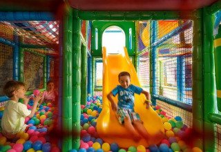 Children playing in a colorful indoor ball pit area with a slide at Camping Aminess Maravea, Istria, Croatia.