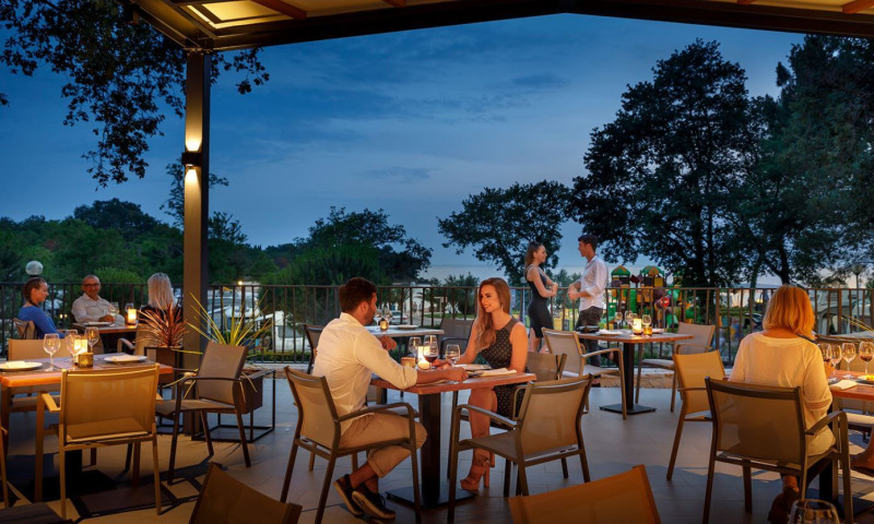 Abendessen auf der Terrasse von Camping Aminess Maravea in Istrien, Kroatien, mit Gästen und stimmungsvollem Licht.