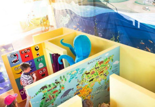 Bambini giocano in un’area giochi interna colorata con murales e polpo blu in Istria, Croazia.