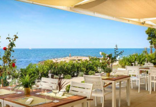 Ristorante all’aperto al Camping Aminess Maravea in Istria, Croazia, con vista mare e cielo soleggiato.