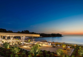 Area pranzo all'aperto al Camping Aminess Maravea in Istria, Croazia, con vista mare al tramonto.