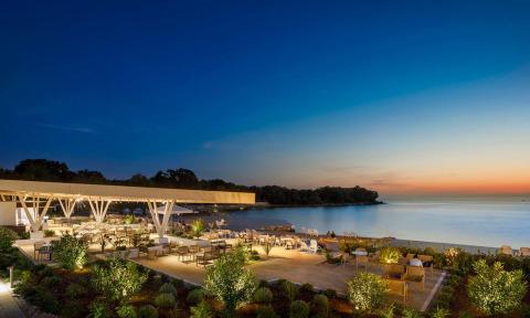 Udendørs spiseområde ved Camping Aminess Maravea i Istrien, Kroatien, med udsigt over havet ved solnedgang.