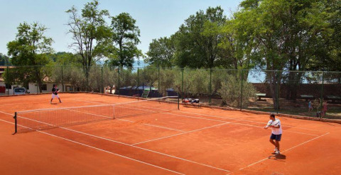 Zwei Personen spielen Tennis auf einem roten Sandplatz im Camping Aminess Maravea, Istrien, Kroatien.