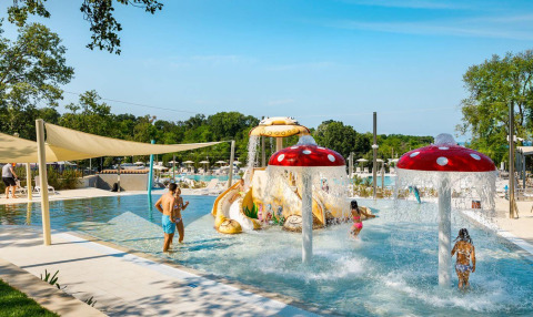 Kinder spielen im bunten Wasserpark mit Pilzfontänen und Rutschen im Camping Aminess Maravea, Kroatien.