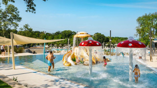 Niños divirtiéndose en la piscina interactiva con fuentes de setas en Camping Aminess Maravea, Croacia.