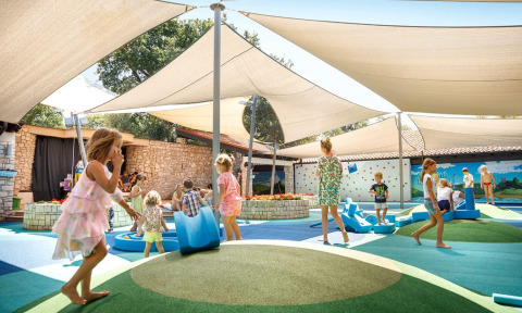 Kinder spielen unter Sonnensegeln auf dem Spielplatz des Camping Aminess Maravea Ferienparks in Istrien, Kroatien.