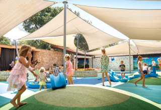 Børn leger under skyggefulde sejl på legepladsen i Camping Aminess Maravea feriepark, Istrien, Kroatien.