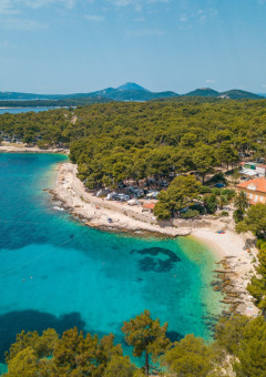 Vista aérea de Camping Cikat en Primorje-Gorski Kotar, Croacia, con bahía turquesa, bosque y playa.