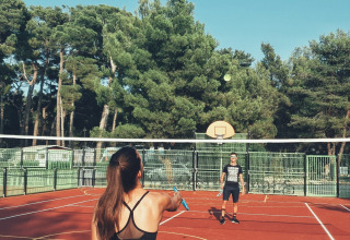 Due persone giocano a badminton su un campo all'aperto circondato da alberi al Camping Cikat, Croazia.