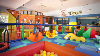 Parque infantil interior en Camping Cikat con juegos coloridos, piscina de bolas y decoración de barco pirata.