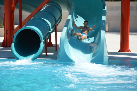 Un ragazzo scende dallo scivolo d’acqua e arriva in piscina al Camping Cikat holiday park in Croazia.