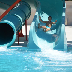 Un niño baja por un tobogán de agua y cae en la piscina del parque vacacional Camping Cikat en Croacia.