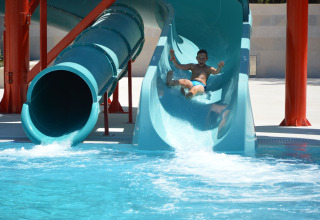 Ein Junge rutscht eine Wasserrutsche hinunter und landet im Pool im Holiday Park Camping Cikat, Kroatien.