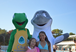 Deux enfants posent avec des mascottes de grenouille et de dauphin à la piscine du Camping Čikat, Croatie.