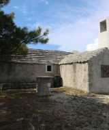 Un edificio rústico de piedra con chimenea blanca, rodeado de naturaleza cerca de Mali Lošinj, Croacia.