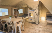 Interieur van een safaritent bij Toftum Bjerge Camping in Denemarken met houten meubels en stapelbedden.