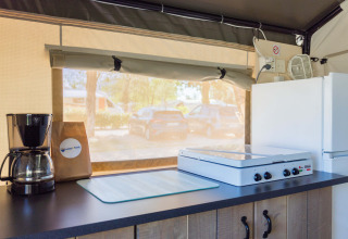 Binnenkeuken van een safaritent met koffiezetapparaat, kookplaat en koelkast bij Camping Stella Maris.