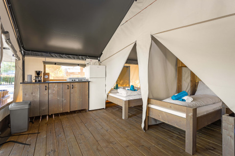 Tenda Safari Comfort al Camping Stella Maris in Croazia con due letti, pavimento in legno e angolo cottura.