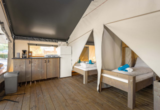 Tienda Safari Comfort en Camping Stella Maris en Croacia con dos camas, suelo de madera y cocina pequeña.