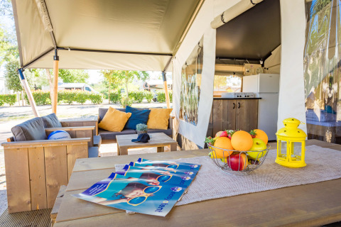 Area soggiorno esterna della Safari Tent Comfort al Camping Stella Maris in Croazia, con divano e cucina.
