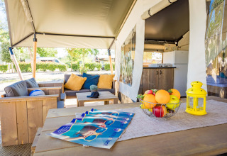 Zona de estar exterior de Safari Tent Comfort en Camping Stella Maris, Croacia, con sofá y cocina visible.
