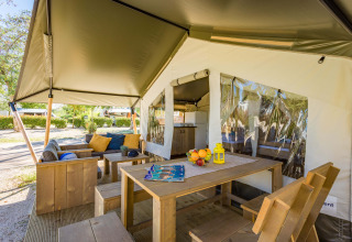 Zona exterior del Safari Tent Comfort en Camping Stella Maris, Croacia, con mobiliario de madera y sombra.