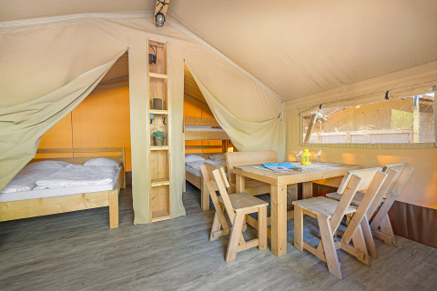 Interno della Safari Tent Lodge al Camping Cikat in Croazia con arredi in legno, letti e zona pranzo accogliente.