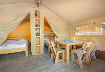 Intérieur du Safari Tent Lodge au Camping Cikat en Croatie avec meubles en bois, lits et coin repas chaleureux.