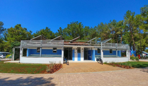 Edificio azul y blanco en Camping Stella Maris, parque vacacional en Istria, Croacia, rodeado de árboles.