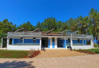 Edificio blu e bianco al Camping Stella Maris, villaggio turistico in Istria, Croazia, circondato da alberi.