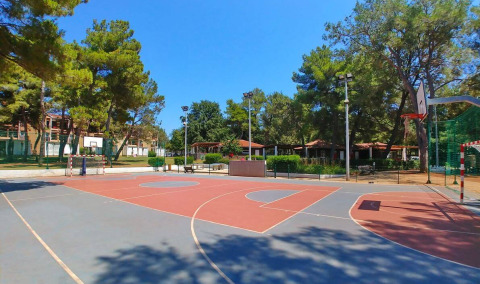 Sportplatz im Freien bei Camping Stella Maris in Istrien, Kroatien, umgeben von Bäumen und Ferienhäusern.