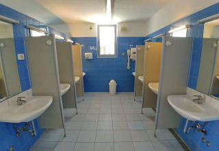 Bagno comune con piastrelle blu e docce private al Camping Stella Maris, Istria, Croazia.