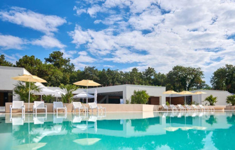 Modern swimming pool with sun loungers and umbrellas at Camping Stella Maris, Istria, Croatia, surrounded by trees.