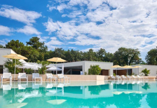 Moderner Poolbereich mit Liegestühlen und Sonnenschirmen im Camping Stella Maris, Istrien, Kroatien, umgeben von Bäumen.